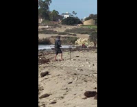 Man black vest pep talk tripod beach