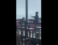 boy holds sandwich in front of chick-fil-a while girl takes pictures. 