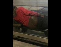 Man at bus stop with buttcheeks leaning on glass 