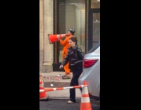 Man orange jumpsuit use traffic cone to speak