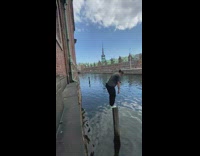Guy jumps building ledge pole in water 