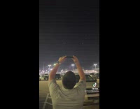 Two guys outside looking at moon on phone 
