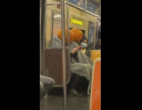 2 subway passengers wear pumpkins on head 