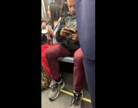 Woman eating a pint of Ben and Jerrys Strawberry Cheesecake ice cream on subway