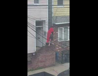 Guy stands on front porch bricks with red cape