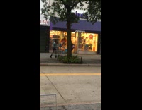 Woman walks in front of claires store with big yellow feather headpiece and orange outfit