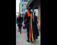 Collab WINY - Men in robe with ribbons walking on sidewalk