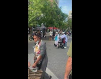 Street performer sings to old woman in wheelchair