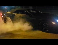 Black car doing a burnout on the ground with lots of smoke