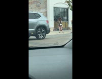 Woman in shiny dress poses on sidewalk