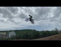 Green jacket guy jumps white dirt bike 
