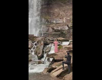 Woman pink dress raise arms rock waterfalls
