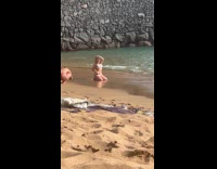 Woman in bikini kneels for beach photo