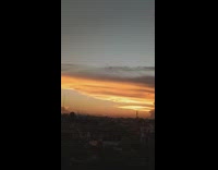 Camera pans right sunset sky clouds houses