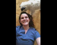 Woman lays on ground dog gives kisses