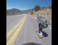 Guy speeds on longboard 
