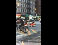 Man rides scooter and pulls kids on a red wagon from behind
