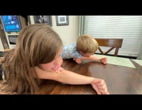 Two kids tries to lick their elbows