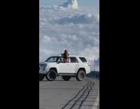 Woman onesie sit on SUV window clouds