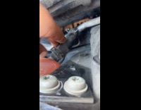 Man searching for coolant leak on car hood 