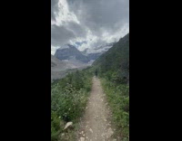 Guy walks down mountain dirt trail clouds 