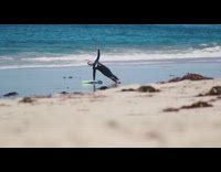 man in black wetsuit warms up on beach