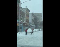 Two guys carry large footrests across crosswalk in winter