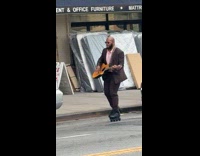 Man in suit skate and play guitar