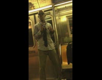 a man in a collard shirt and glasses dances on a subway train 