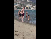 Woman in bikini kneels and faces the ocean at the beach