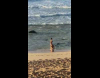 Woman black bikini side pose tiptoe beach 