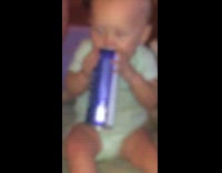 Indoors baby drinks beer from can on bed