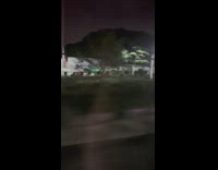 Guy on the street riding a scooter all the way in the front 
