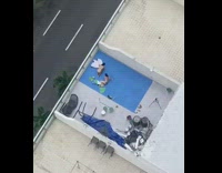 Two women bikini exercise blue yoga mat rooftop