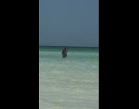 Man with cap splashes water in the air at the beach