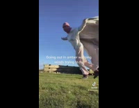 Girl using blanket to try to fly in windy area on grass 