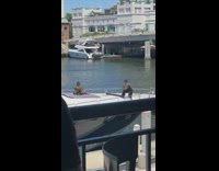Man in black and gold top sits on the deck of the boat