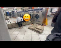 Two women tries to fit carpet inside laundromat