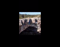 Guy hangs from very tall cave cliffside 