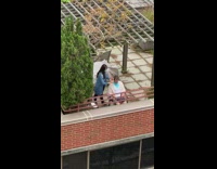 Lady gives haircut outside on building rooftop 
