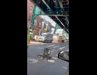 Car passes by trash can in middle of street 