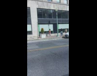 Woman in beige dress orange hair poses on the sidewalk