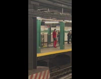 Guy in tall red boots in subway station singing and dancing