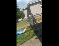 Girl lays in plastic kiddie pool friend hose 