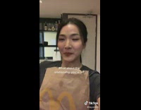 Lady Talks while she Holds a Bag of McDonalds Meal