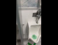 Tall guy looks over stall in bathroom