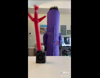 Girl in purple inflatable wavy arm guy costume 