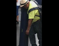 Drunk guy in neon green shirt holds onto pillar at the subway