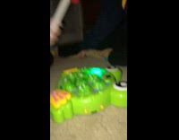 Two girls watch friend hit childrens frog toy with hammer