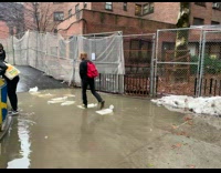 People crossing flooded sidewalk on sandbag path